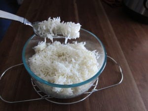 instant pot fluff rice with fork, rice in glass bowl on a metal rack