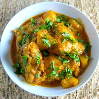 Indian Instant Pot Chicken Curry with cilantro in white bowl on straw placemant