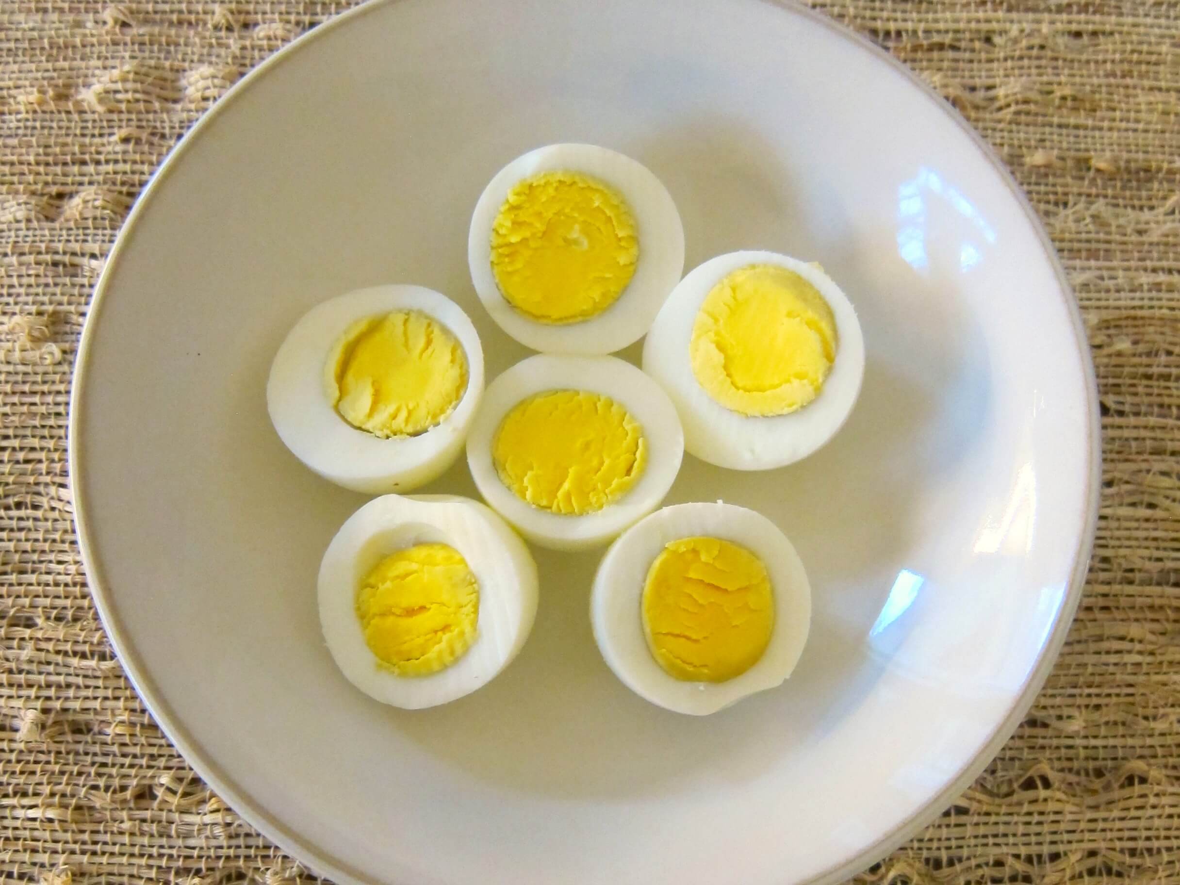 Three Instant Pot eggs cut into half in a white bowl, yellow side up