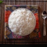 Instant Pot Jasmine Rice in white bowl on straw placemat with colorful napkin and a spoon - Paint the Kitchen Red