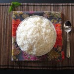 Instant Pot Jasmine Rice in white bowl on flowery colorful napkin and straw placemat with a spoon- Paint the Kitchen Red