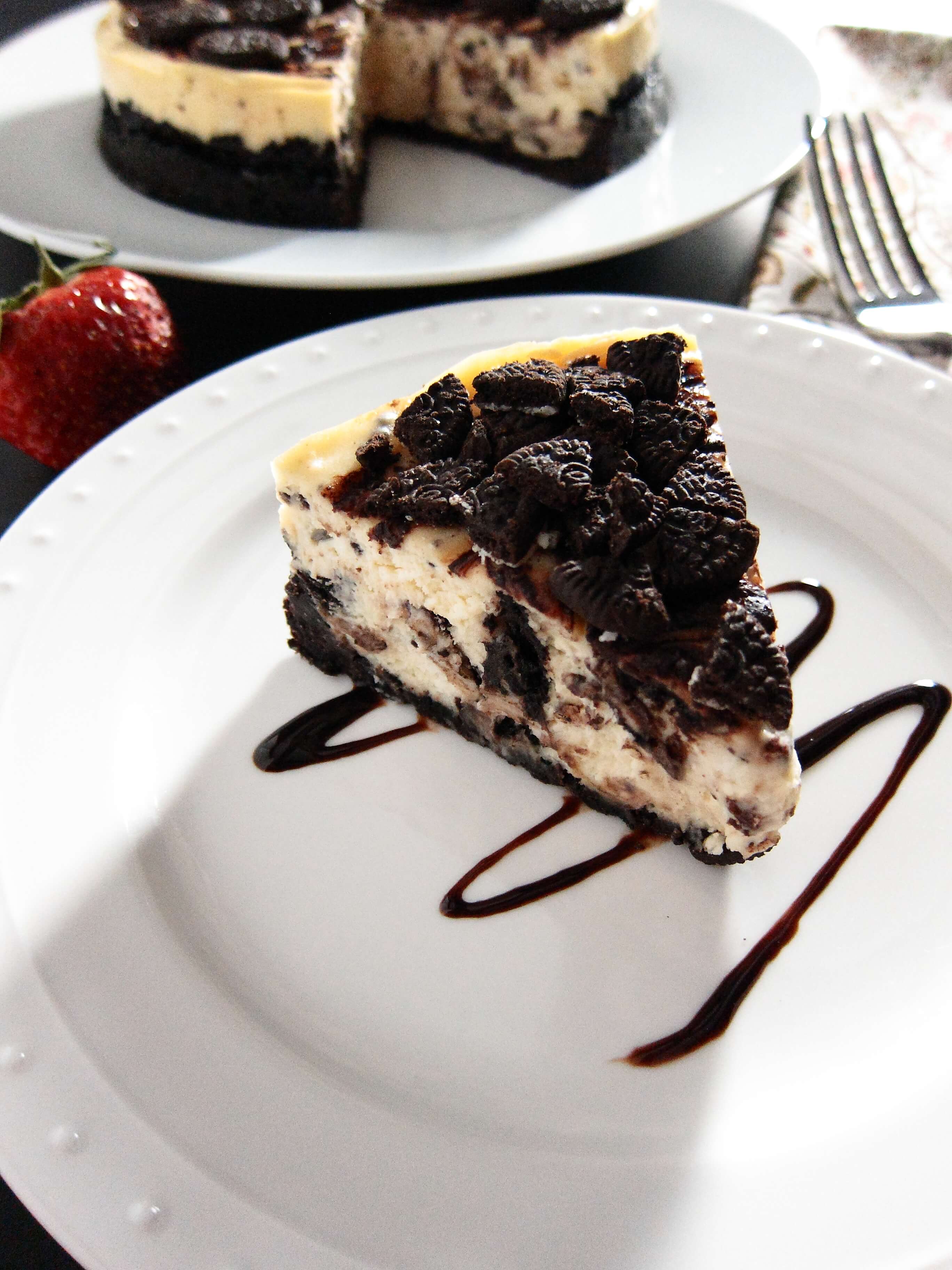 Instant Pot Oreo Cheesecake slice on a white plate with swirled chocolate sauce below