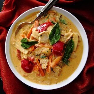 Instant Pot Thai Red Curry with colorful vegetables in white bowl with spoon on rich red napkin.