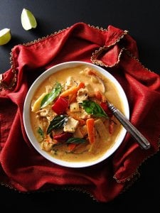 Instant Pot Thai Red Curry Chicken on red napkin with gold and two pieces of lime on black surface - Paint the Kitchen Red
