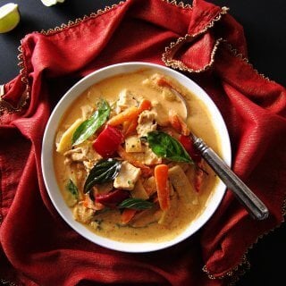 Instant Pot Thai Red Curry Chicken on red napkin with gold and two pieces of lime on black surface - Paint the Kitchen Red