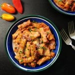 Blue bowl with pasta, sauce and shredded cheese and parsley.