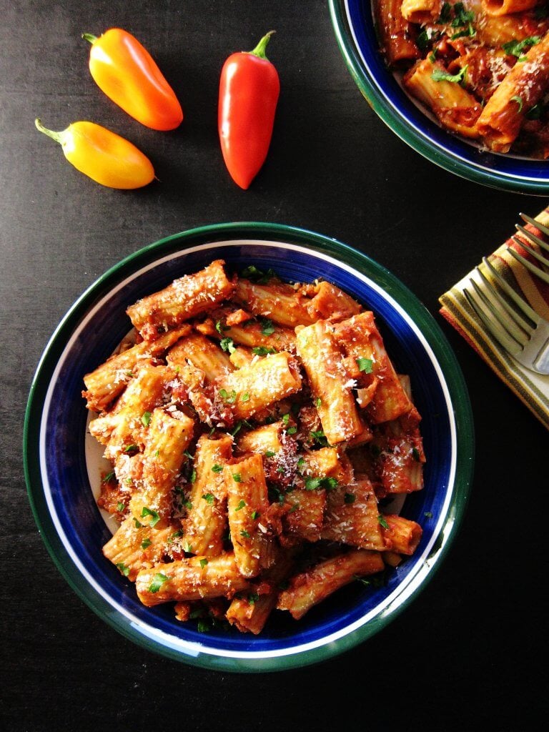 Instant Pot Vegetarian Pasta in blue and green bowls with multi colored bell pepper on black background, with napkin and forks - Paint the Kitchen Red