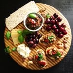 Instant Pot Ratatouille - round wooden board with cheeses, basil, olives, crostini, cherries, nuts, crackers