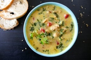 Instant Pot Chicken Curry Soup - yellow colored soup topped with cilantro in teal bowl on black background with french bread slices - Paint the Kitchen Red