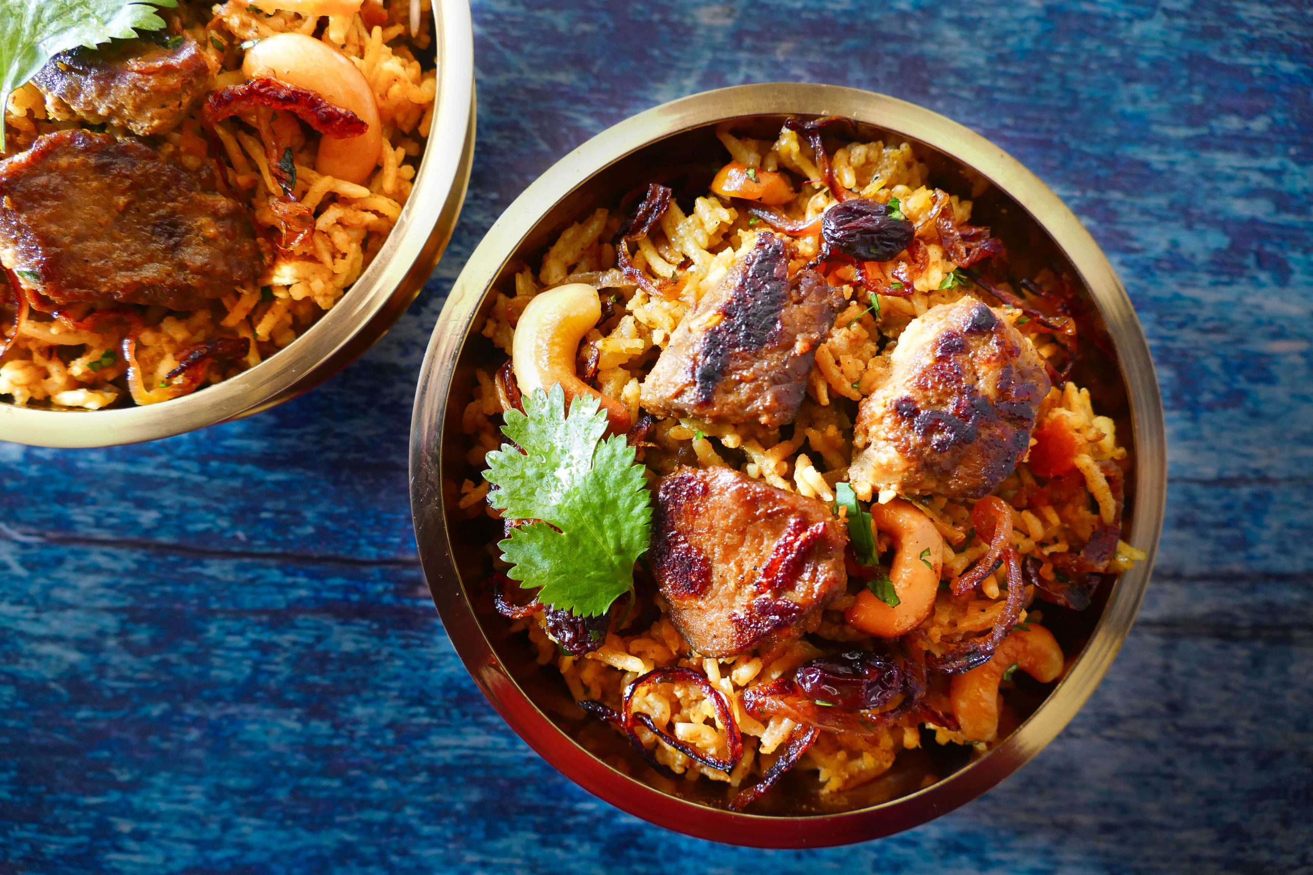 Instant Pot Biryani with Lamb landscape with 2 brass bowls on blue table - Paint the Kitchen Red