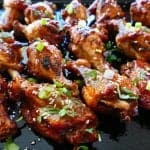Instant Pot Teriyaki Wings cooked on dark background with green onions and sesame seeds sprinkled on top