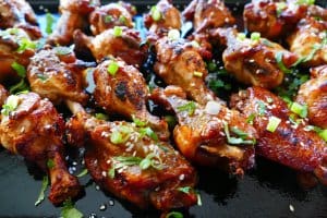 Instant Pot Teriyaki Wings cooked on dark background with green onions and sesame seeds sprinkled on top - Paint the Kitchen Red