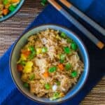 Instant Pot Fried Rice - bowl of rice with vegetables garnished with green onions in blue bowl on blue napkin with chopsticks