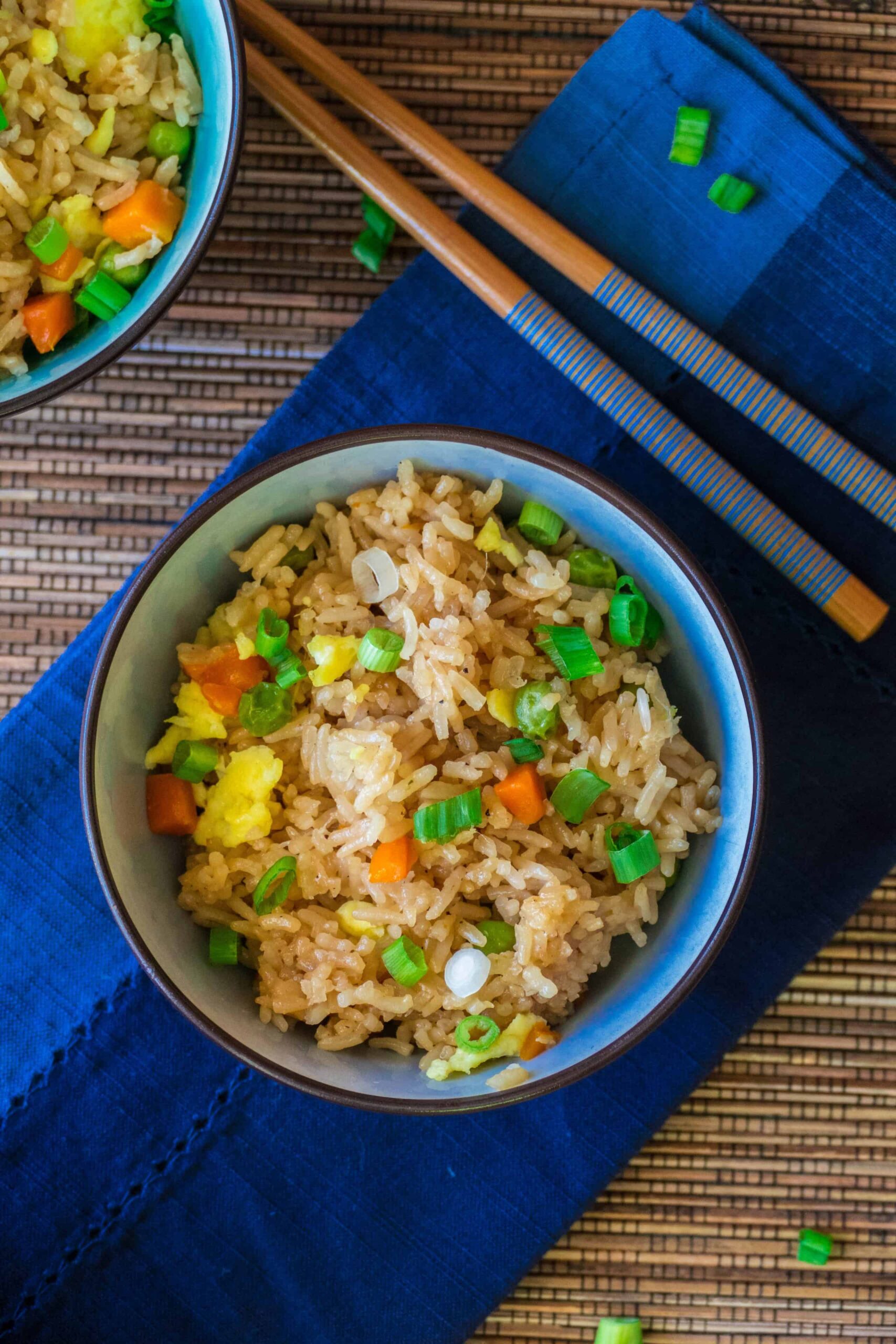 Instant Pot Fried Rice - bowl of rice with vegetables garnished with green onions in blue bowl on blue napkin with chopsticks