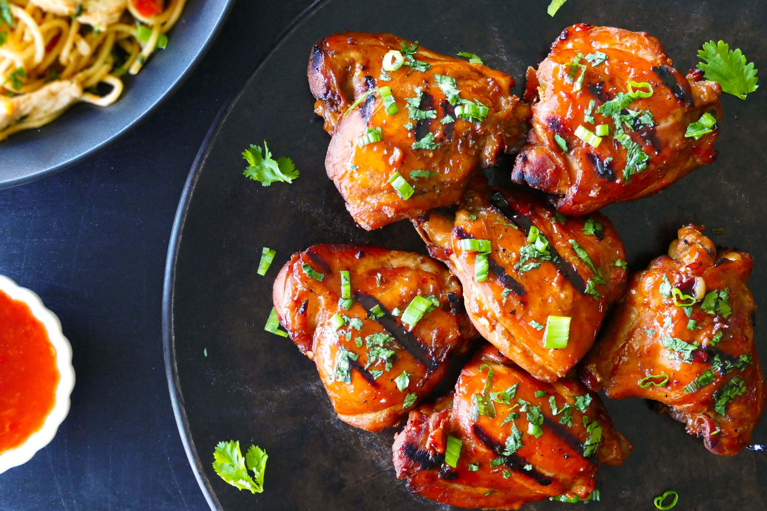 Instant Pot Thai Grilled Chicken Thighs on dark background with sprinkled cilantro and green onions