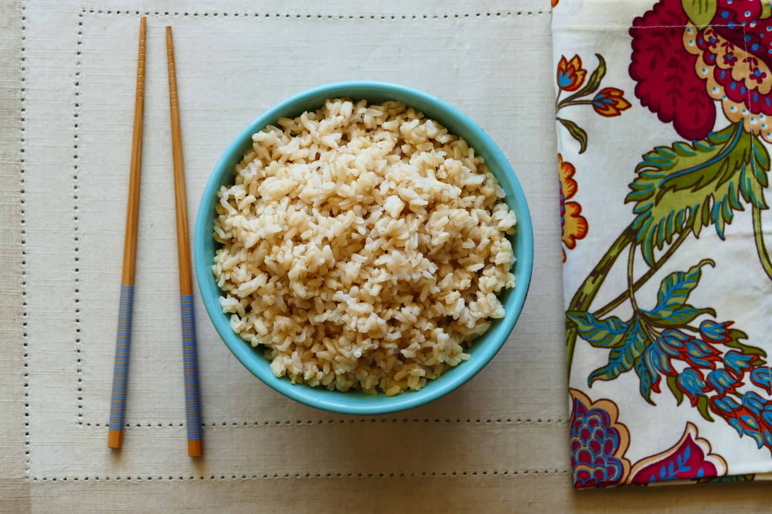 Instant Pot Brown Rice P1 turquoise bowl with brown rice with flowered napkin in background