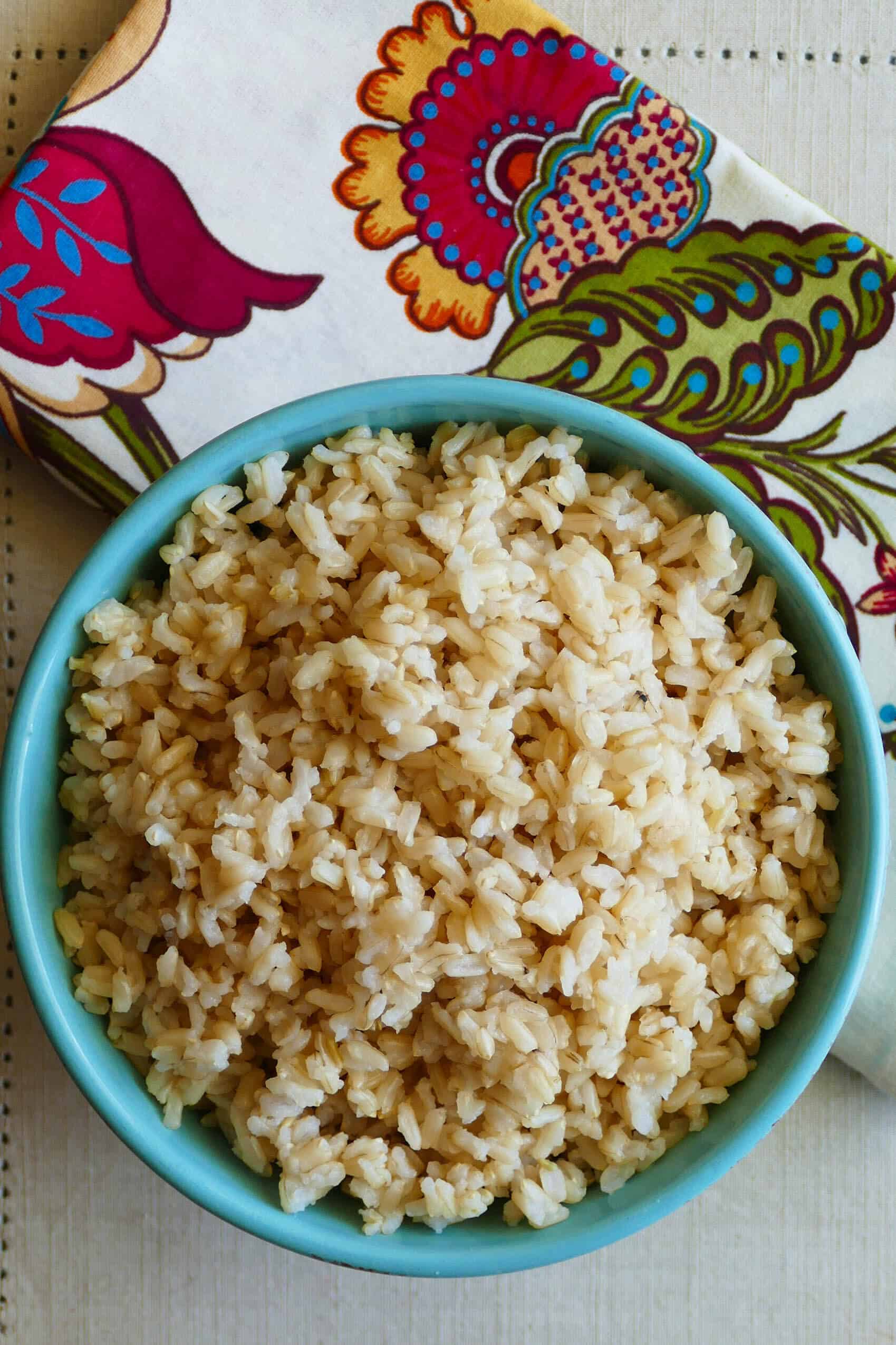 Instant Pot Brown Rice P1 turquoise bowl with brown rice with flowered napkin in background - Paint the Kitchen Red