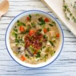 Instant Pot Cream of Chicken Soup in flower painted bowl garnished with bacon bits and scallions, napkin and fresh thyme in background