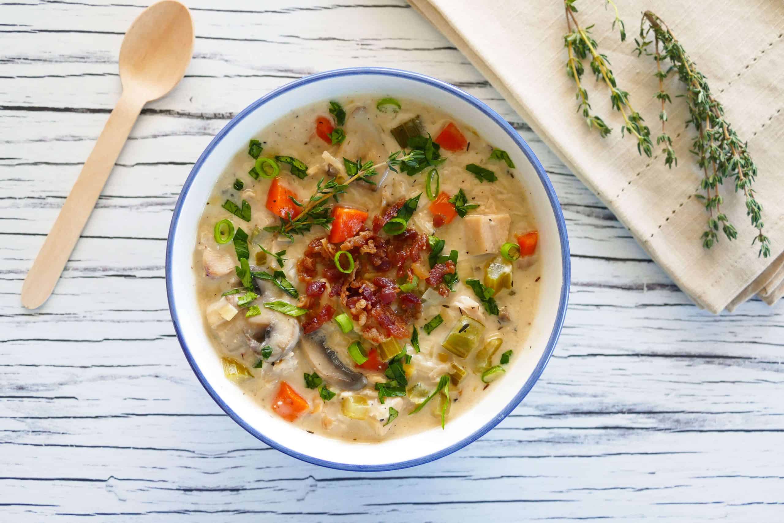 Instant Pot Cream of Chicken Soup in flower painted bowl garnished with bacon bits and scallions, napkin and fresh thyme in background