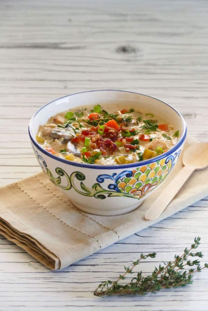 Instant Pot Cream of Chicken Soup in flower painted bowl garnished with bacon bits and scallions, napkin and fresh thyme in background