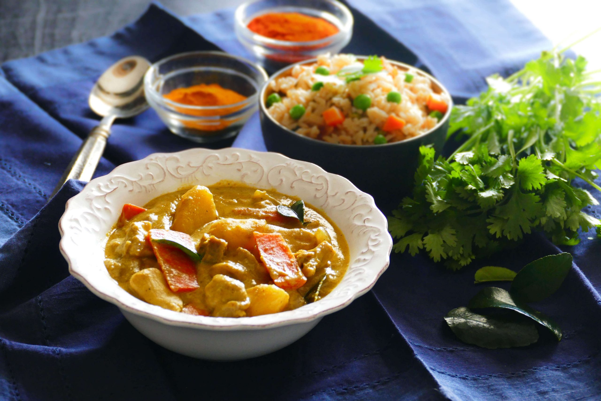 Instant Pot Thai Yellow Curry with Chicken in white bowl on blue napkin, with fried rice in another bowl