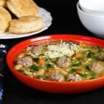 Instant Pot Italian Wedding Soup - Orange bowl with beans, carrots, meatballs, spinach, parmesan and bread and empty bowls in the background - Paint the Kitchen Red