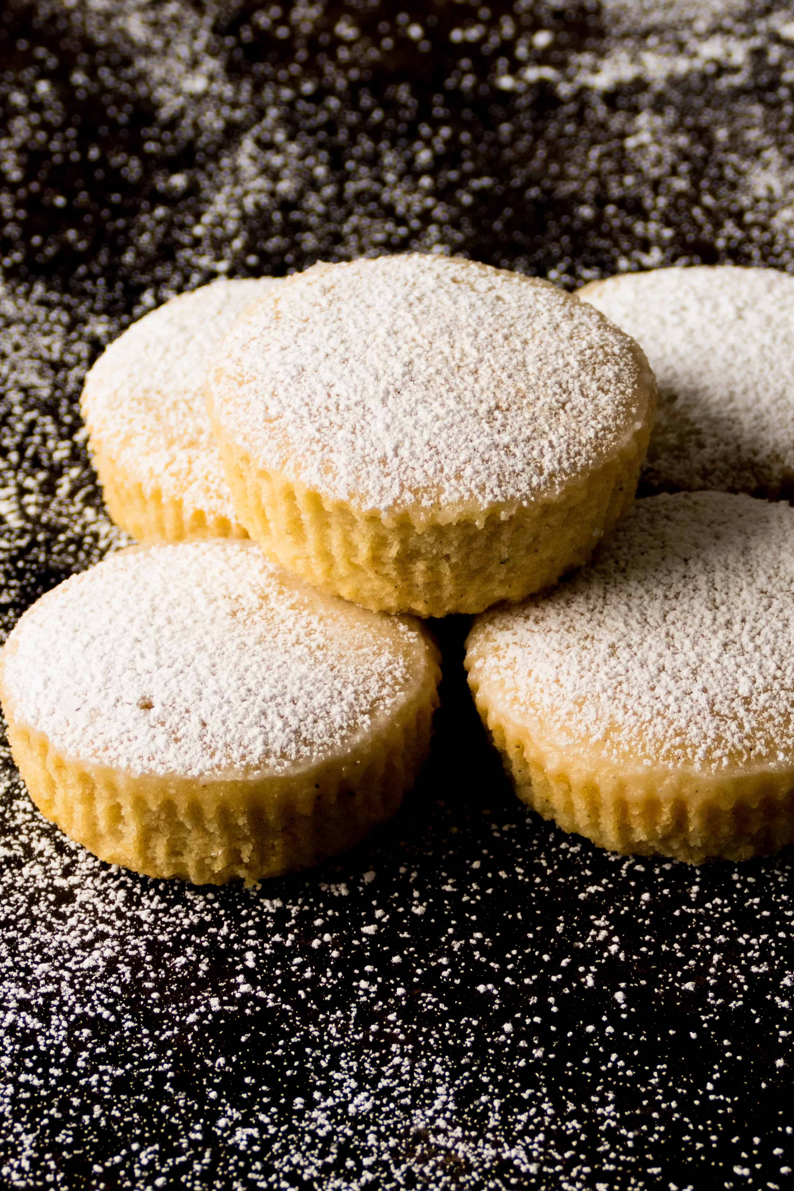 Instant Pot Cupcakes Cardamom Pound Cakes stacked on a black background and dusted with confectioners sugar - Paint the Kitchen Red