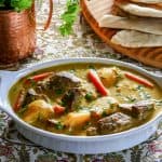 Instant Pot Beef Curry in white oval serving dish with cilantro and naan in the background - Paint the Kitchen Red.jpg