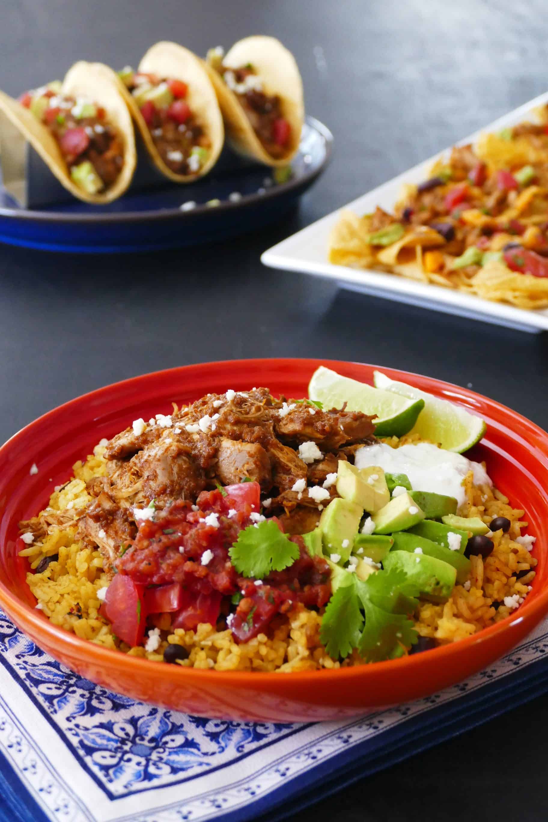 Instant Pot Chicken Tinga rice bowl in orange bowl with chicken tinga tacos and nachos in the background 