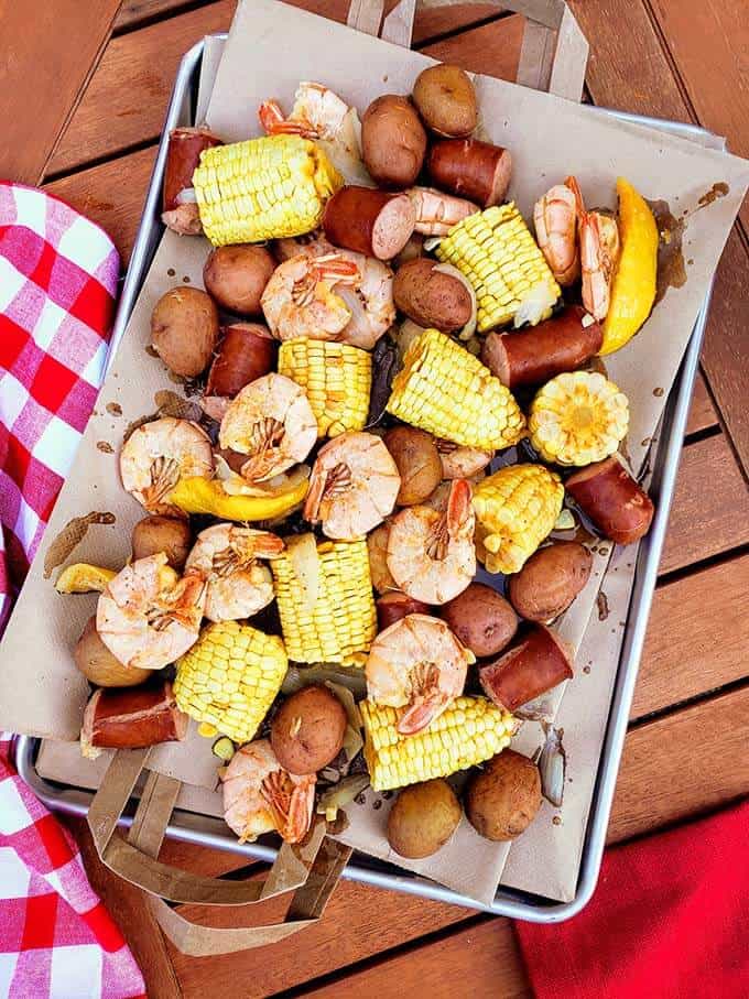 Tray lined with paper and boiled shrimp, potatoes, sausage, corn