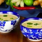 2 Asian-print bowls of Instant Pot Thai coconut soup with herbs in the background