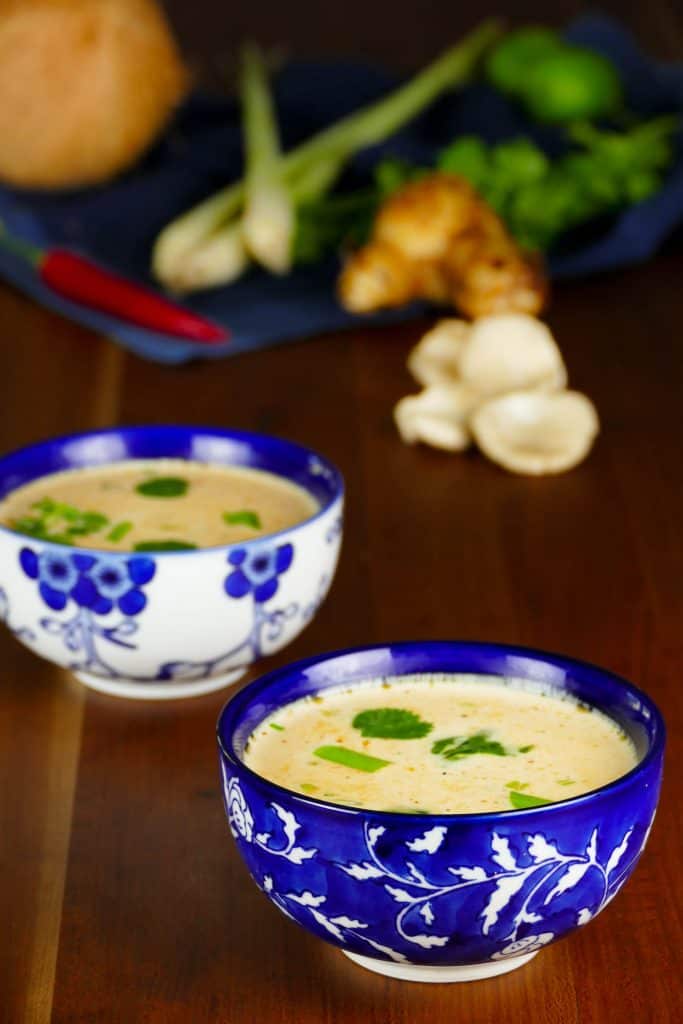 2 Asian-print bowls of Instant Pot Thai coconut soup with herbs in the background