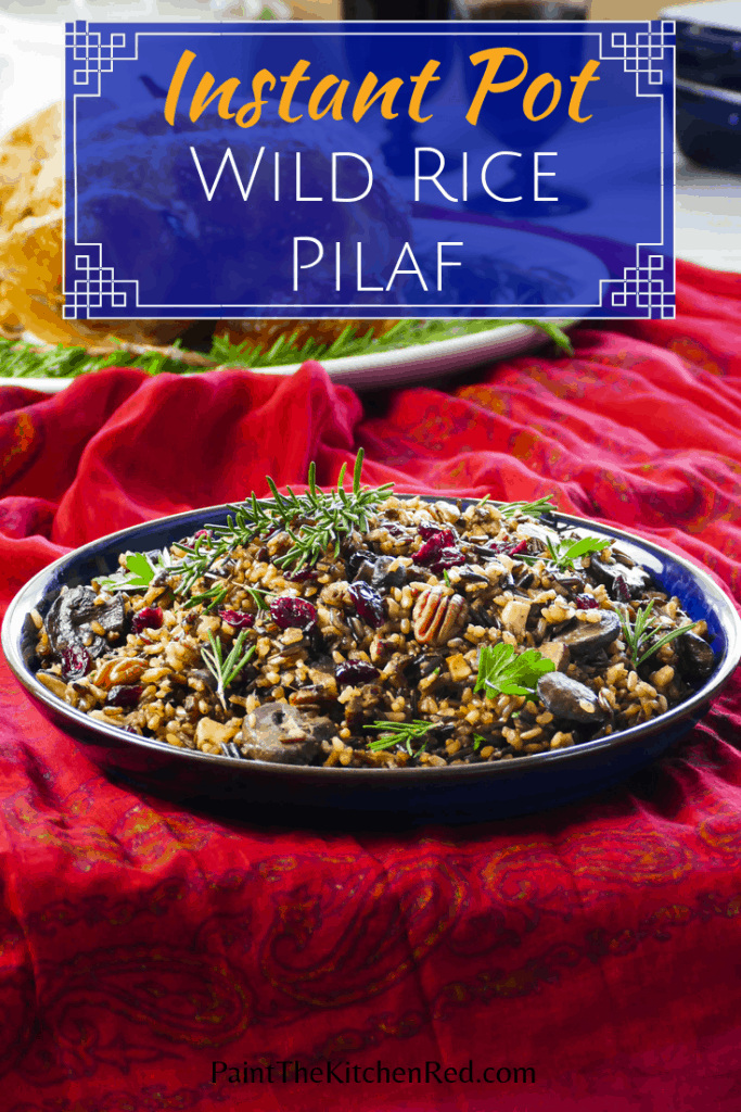 Instant Pot Wild Rice Pilaf Pinterest Pin - rice topped with pecans and dried cranberries in a blue bowl on a festive red tablecloth- Paint the Kitchen Red