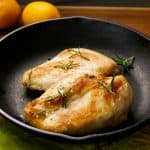 2 Sous Vide Chicken Breasts in a cast iron pan with lemons in the background- Paint the Kitchen Red