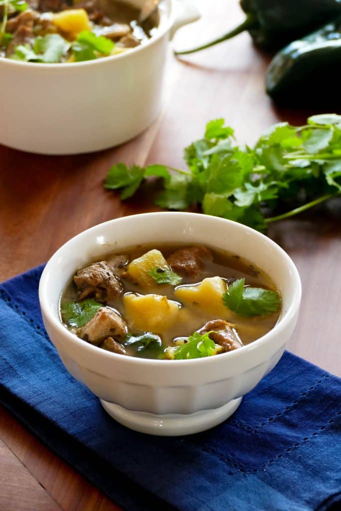 Instant Pot Pork and Hatch Chile Soup in a white bowl on a blue napkin