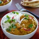 Instant Pot chicken korma curry with rice in a bowl with naan bread in the background