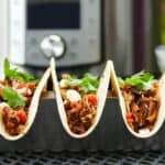 Three Instant Pot Pulled Pork Tacos on a table