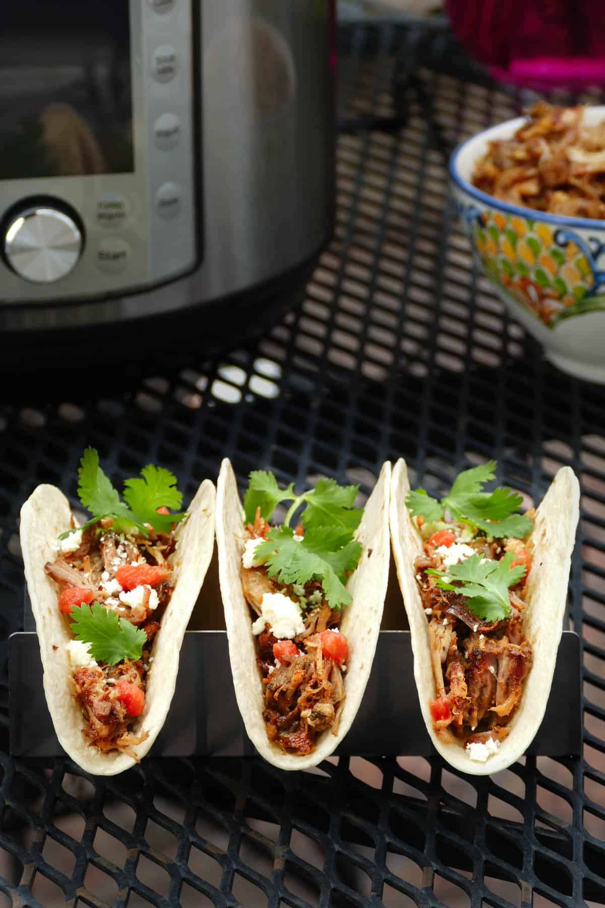 Three Instant Pot Pulled Pork Tacos on a table