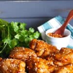 Instant Pot Korean Chicken two thighs and four drumsticks on a dark background, garnished with sesame seeds