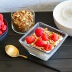 bowl of yogurt with granola and raspberries