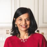 Neena in red sweater slight smiling with white cabinets in background