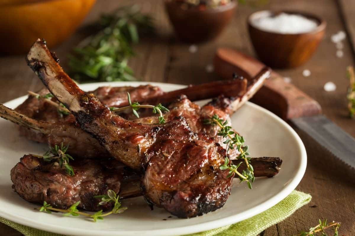 lamb chops on a white plate garnished with thyme