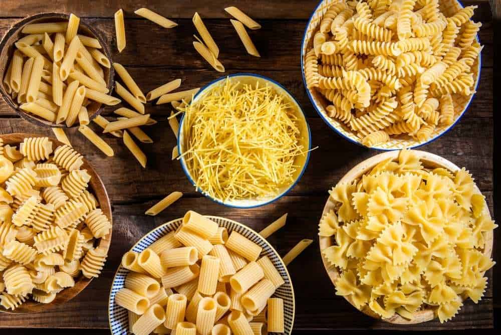 Assorted pastas in bowls including rotini, farfalle, penne, rigatoni