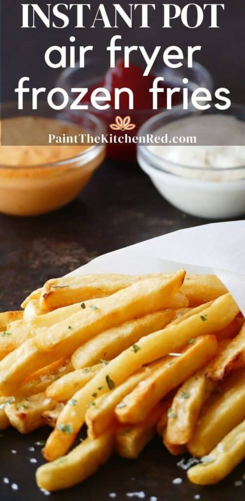 French fries with sea salt and parsley wrapped in white parchment and three glass bowls with condiments