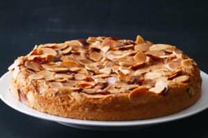 Cake on white plate with slivered almonds baked to a golden brown