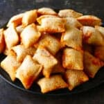 Air fryer pizza rolls stacked on a dark plate