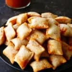 Air fryer pizza rolls stacked on a dark plate