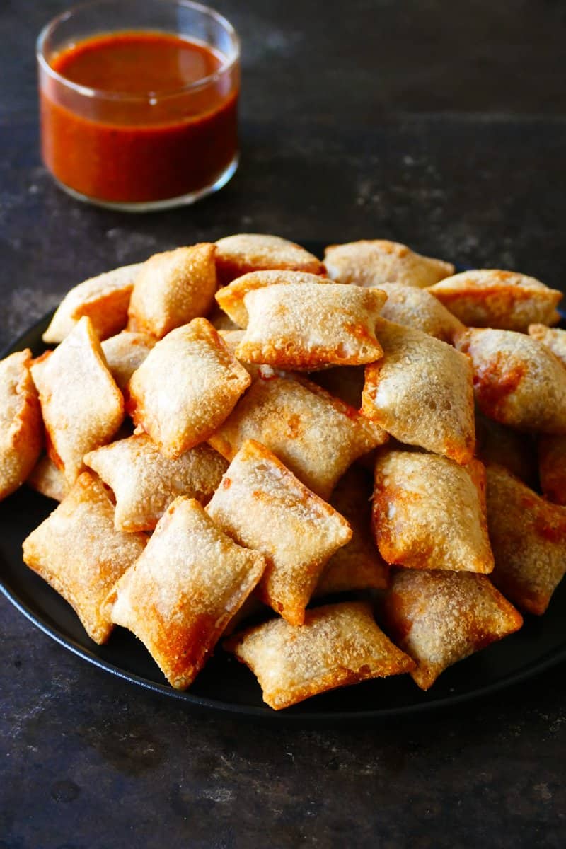 Air fryer pizza rolls stacked on a dark plate