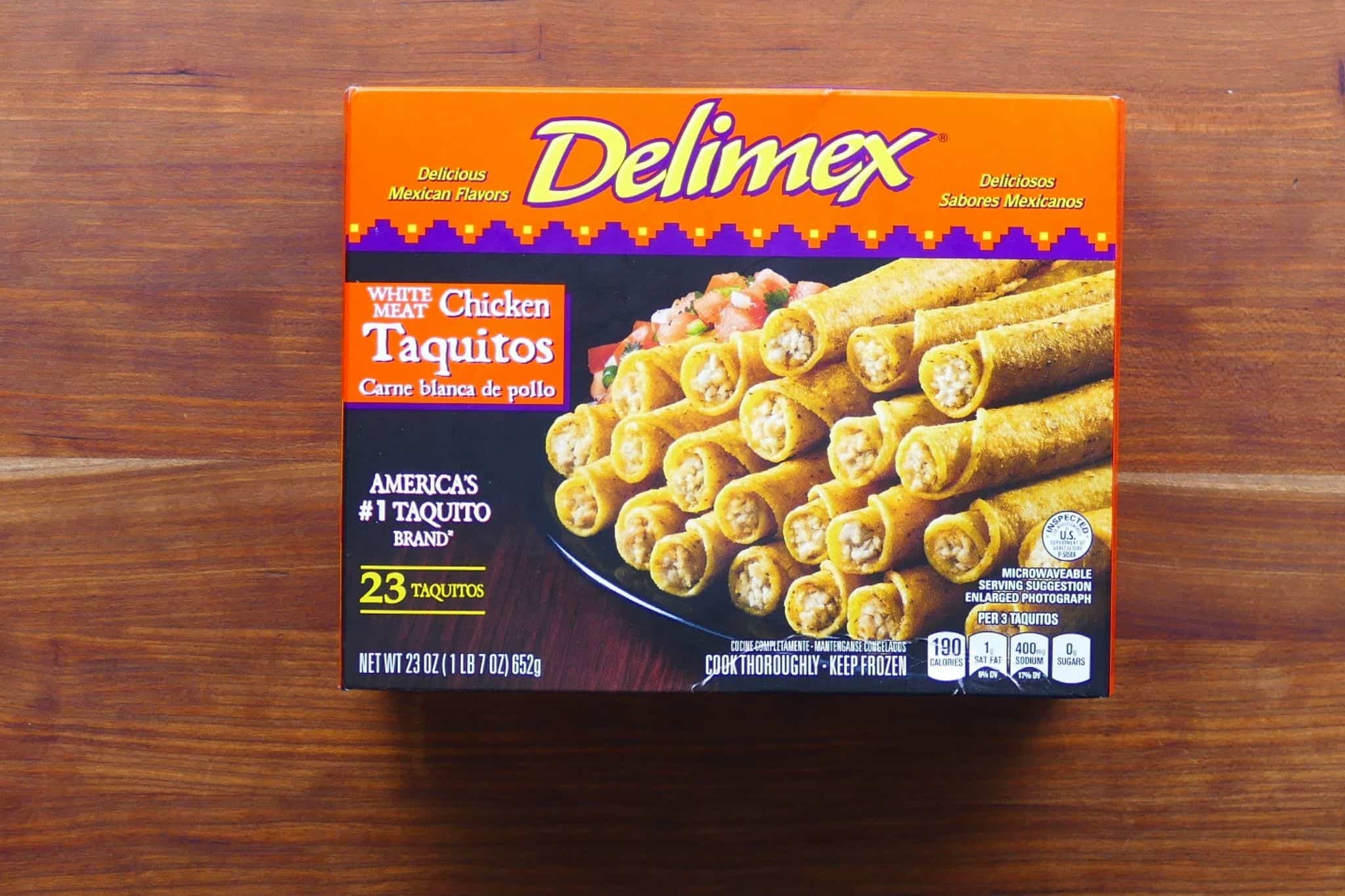 Delimex brand white meat chicken taquitos box with orange and purple design and stacked taquitos photo
