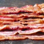 Strips of cooked bacon on black background.